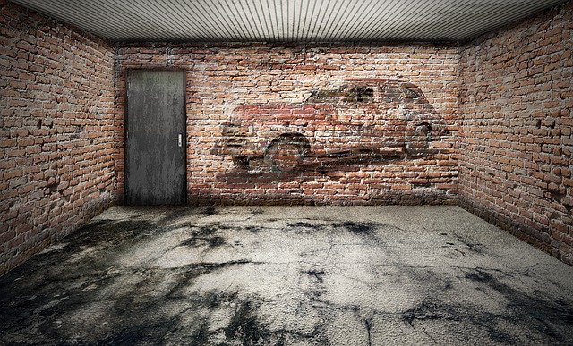 Garáž s tehlovou stenou, na ktorej je namaľované auto